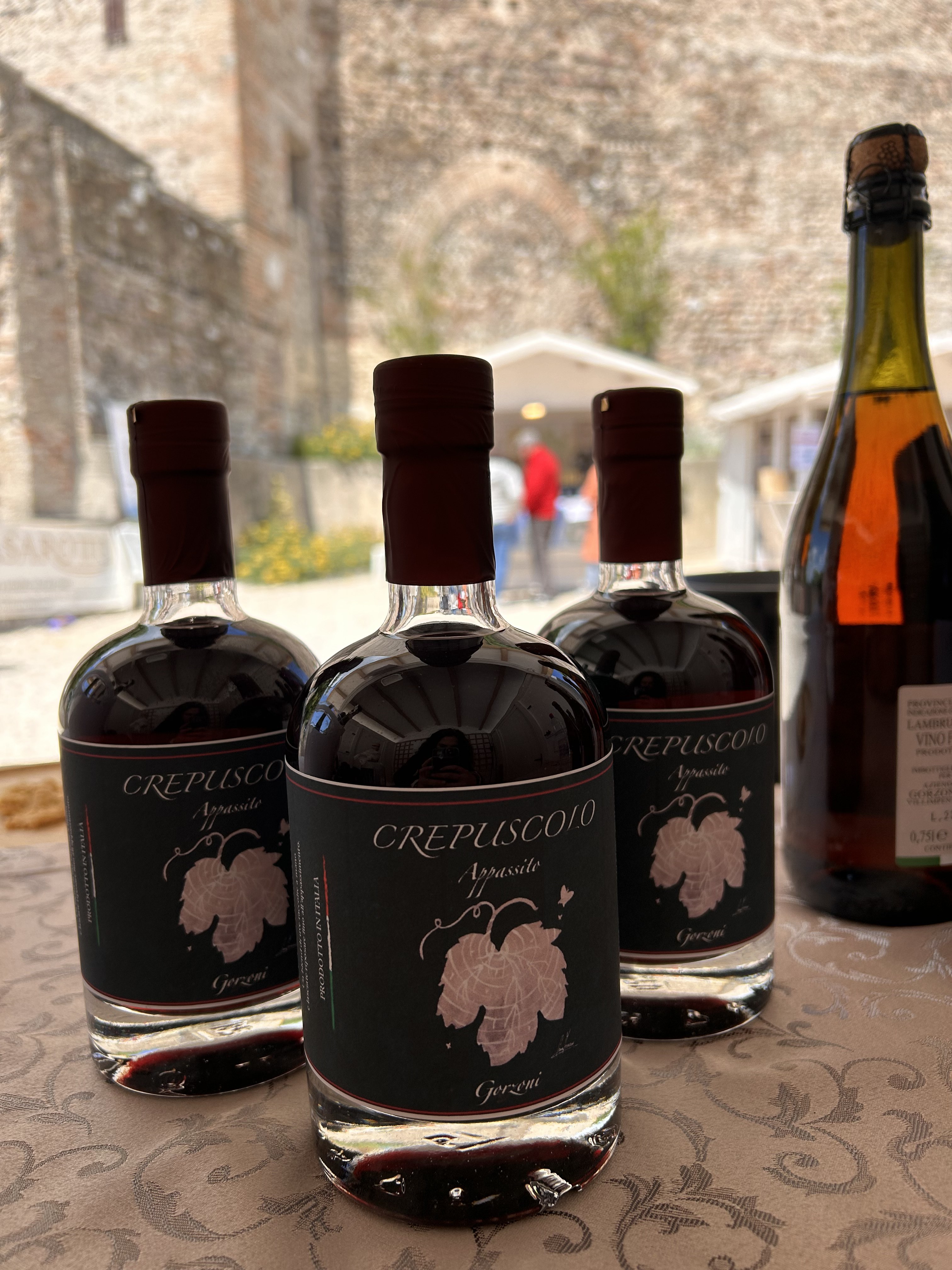Bottiglie Crepuscolo Appassito con castello medievale di Volta Mantovana sullo sfondo